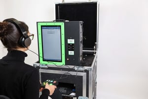 A woman in a black sweater sits in front of a ClearMark ballot marking device to cast a ballot
